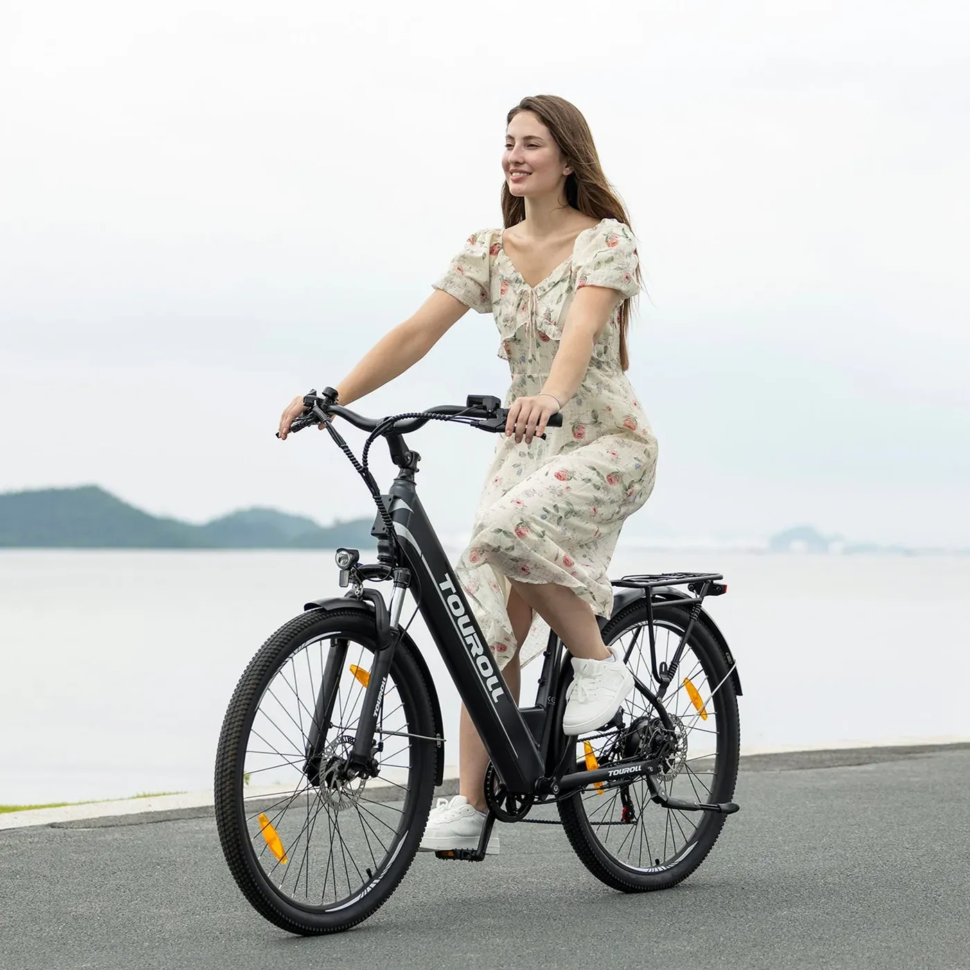 Une cycliste en robe roule sur un Touroll J1 ST noir le long d'un lac