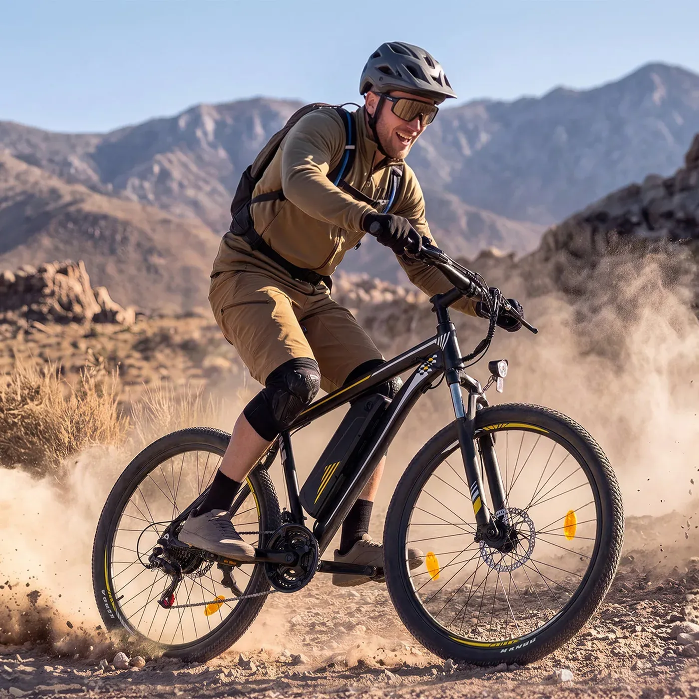 Un cycliste casqué roule sur une piste de terre poussiéreuse avec le Touroll U1, montagnes en arrière-plan